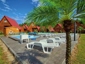 a row of white lounge chairs next to a swimming pool at Cottage in Jaros awiec near Seaside Beach in Jarosławiec