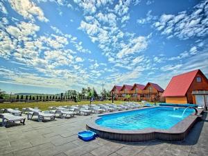 a swimming pool with white chairs and a blue sky at Cottage in Jaros awiec near Seaside Beach in Jarosławiec