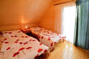 a bedroom with two beds with red flowers on them at Cottage in Jaros awiec near Seaside Beach in Jarosławiec +18 photos