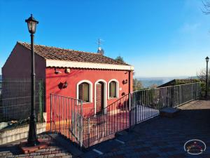 ein rotes Haus mit einem Zaun und einer Straßenbeleuchtung in der Unterkunft Agriturismo Dolcetna in SantʼAlfio