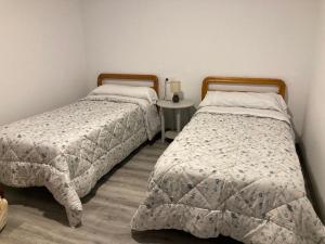 dos camas sentadas una al lado de la otra en un dormitorio en Apartamento Turístico Cervantes 18, en Losar de la Vera