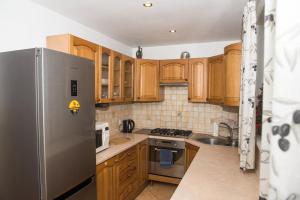 Una cocina con gabinetes de madera y un refrigerador de acero inoxidable. en Parkowa House, en Cracovia