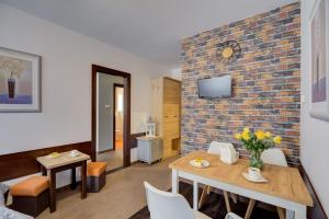 - un salon avec une table et des chaises ainsi qu'un mur en briques dans l'établissement Apartamenty Krynica-Zdrój Karolina, à Krynica-Zdrój