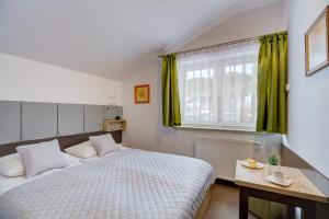 - une chambre avec un lit et une fenêtre avec des rideaux verts dans l'établissement Apartamenty Krynica-Zdrój Karolina, à Krynica-Zdrój