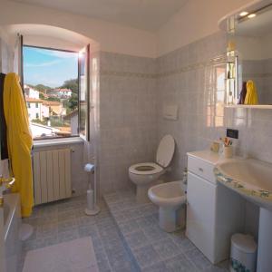 ein Bad mit einem WC, einem Waschbecken und einem Fenster in der Unterkunft LE SOLEIL DOREE' MAISON Wi-Fi VACATIONS LERICI 5 TERRE in Pitelli