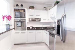 una cucina bianca con armadietti bianchi ed elettrodomestici in acciaio inossidabile di DISFRUTA SUNNY ISLES OCEAn 1206 STR-02637 a Miami Beach