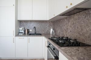 een keuken met witte kasten en een fornuis met oven bij Klevų apartamentai in Klaipėda
