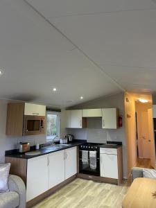 una pequeña cocina con armarios blancos y un sofá en Coastal retreats, Beech rise, primrose valley, en Filey