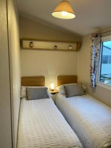 twee bedden in een kleine kamer met een raam bij Coastal retreats, Beech rise, primrose valley in Filey