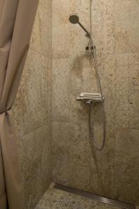 een douche met een douchekop in de badkamer bij Klevų apartamentai in Klaipėda