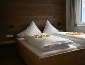 two beds with white sheets and yellow bows on them at Alma&Antonia in Schladming