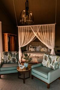 a bedroom with a bed and two chairs and a table at Kifaru Luxury Lodge in Outjo