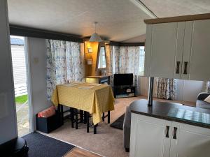 eine Küche und ein Wohnzimmer mit einem Tisch und einem gelben Tischtuch in der Unterkunft Lakeside in Chichester