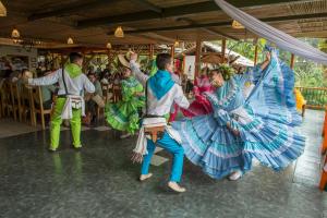 a group of people in costumes dancing in front of a crowd at Hacienda Charrascal Coffe Farm in Manizales