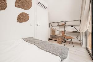 a white bedroom with a bed and a chair at AMORZELAS in Dębki