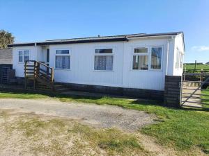 a white house with a fence in front of it at On farm Chalet, sleeps 6, Rhoshirwaun in Aberdaron