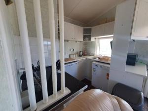 a small kitchen with white cabinets and a table at On farm Chalet, sleeps 6, Rhoshirwaun in Aberdaron
