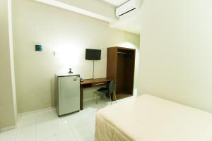 a room with a desk and a bed and a refrigerator at Grace Setia Hotel in Surabaya