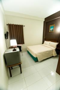 a bedroom with a bed and a table with a lamp at Grace Setia Hotel in Surabaya