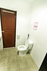 a bathroom with a toilet and a brown door at Grace Setia Hotel in Surabaya