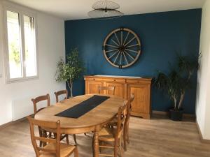 a dining room with a wooden table and a large wheel on the wall at Maison chaleureuse à la campagne in Camps-en-Amiénois