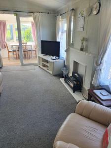 a living room with a couch and a television at On farm Chalet, sleeps 6, Rhoshirwaun in Aberdaron