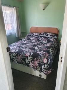 a bedroom with a bed with a floral comforter at On farm Chalet, sleeps 6, Rhoshirwaun in Aberdaron