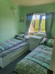 a bedroom with two twin beds and a window at On farm Chalet, sleeps 6, Rhoshirwaun in Aberdaron