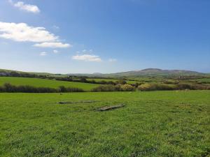 a field with green grass and a blue sky at On farm Chalet, sleeps 6, Rhoshirwaun in Aberdaron