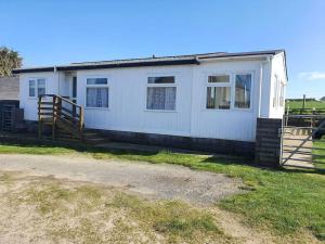 a white house with a fence in front of it at On farm Chalet, sleeps 6, Rhoshirwaun in Aberdaron