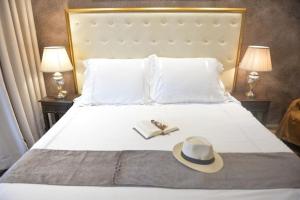 a bed with a hat and a book and two lamps at angela studios in Paleokastritsa