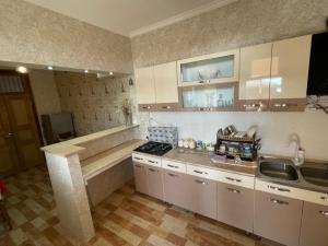 a kitchen with white cabinets and a stove and a sink at Jibghashvilebi's house in Lagodekhi