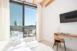 Un dormitorio con una cama y un escritorio y una ventana. en Placeta Vella Turismo de Interior, en Caimari