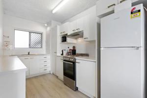 a kitchen with white cabinets and white appliances at Maroochy Sands Holiday Apartments in Maroochydore