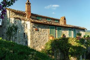 an old stone building with green shutters and a cross at Celle di lecchi nel Chianti in San Sano