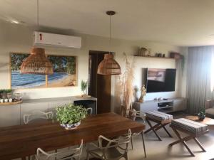 ein Wohnzimmer mit Tisch und Stühlen und einem Fernseher in der Unterkunft Apartamento 3/4 maravilhoso no Village das Acácias in Praia do Forte