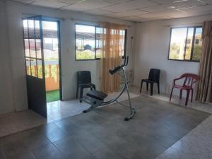 una habitación con un gimnasio con sillas y una cinta de correr en Casa de Alexis, en Puerto Baquerizo Moreno