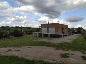 un piccolo edificio di mattoni in mezzo a un campo di Abrazo del Sol Villa Serrana. Lavalleja a Villa Serrana