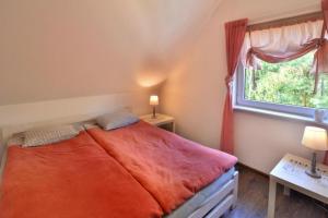 a bedroom with a bed with an orange blanket and a window at Holiday homes, Rusinowo in Rusinowo