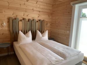 a bedroom with a large white bed with wooden walls at Ferienhaus am Schaalsee, Zarrentin in Zarrentin