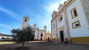 Una iglesia con una torre y un árbol delante de ella. en Casa 33, en Veiros