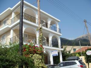 a white building with cars parked in front of it at Captain Georgio Apartments in Poros