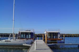 zwei Boote, die an einem Dock im Wasser angedockt sind in der Unterkunft Houseboat Floating House "Luisa", Ribnitz-Damgarten in Ribnitz-Damgarten