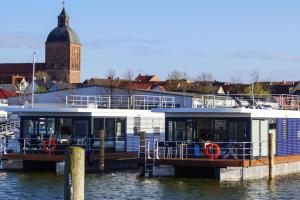 Łódź zakotwiczona jest w doku w wodzie w obiekcie Houseboat Floating House "Luisa", Ribnitz-Damgarten w mieście Ribnitz-Damgarten