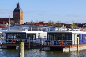 Ein Boot liegt an einem Dock im Wasser. in der Unterkunft Houseboat Floating House "Luisa", Ribnitz-Damgarten in Ribnitz-Damgarten