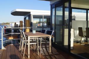 uma mesa de madeira e cadeiras no deque de um barco em Houseboat Floating House "Luisa", Ribnitz-Damgarten em Ribnitz-Damgarten