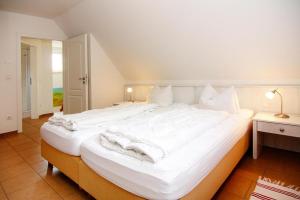 un grande letto bianco con lenzuola e cuscini bianchi di Holiday home in Zirchow a Zirchow