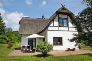 una casa bianca con tetto di paglia e patio di Holiday home in Zirchow a Zirchow