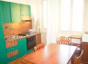 una cucina con armadi verdi e tavolo in legno di Cathy Apartment a Roma