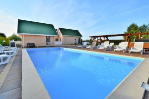 a large swimming pool with chairs and a house at Holiday resort, Osieki in Osieki